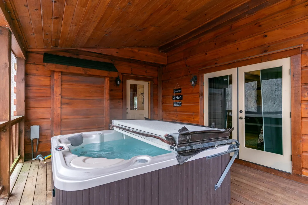 An indoor hot tub set against wooden walls with glass doors leading outside, blending cozy indoor comforts with scenic nature views. The space is intimate, perfect for unwinding or sharing special moments.
